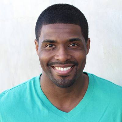An elderly couple smiling together, with the man wearing glasses, both posing for a photo.