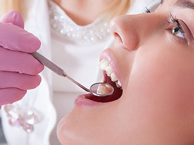 The image shows a dental professional performing oral care on a patient s mouth, with the focus on the use of dental instruments.