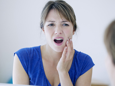 The image shows a woman with her mouth open, seemingly reacting with surprise or shock, while holding her face with both hands.