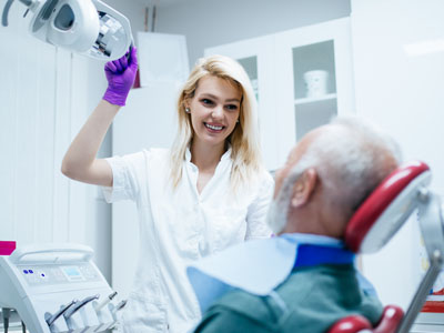 A dental professional assisting an elderly patient with a dental procedure.