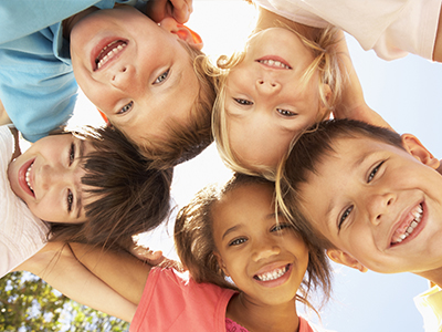 A group of children smiling at the camera from various angles.