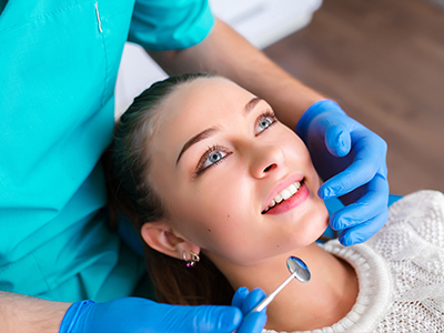 A dental hygienist performing a teeth cleaning procedure on a patient s mouth using specialized tools.