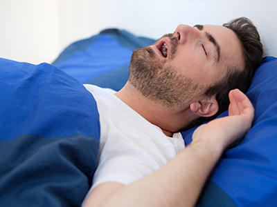 A man asleep in bed with his head on a pillow.