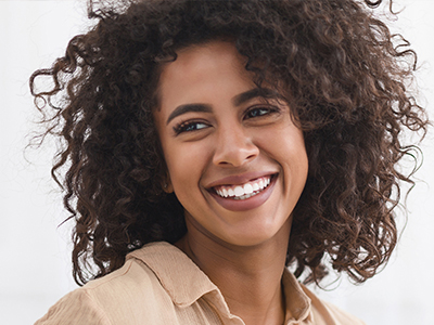 The image features a woman with curly hair smiling at the camera.